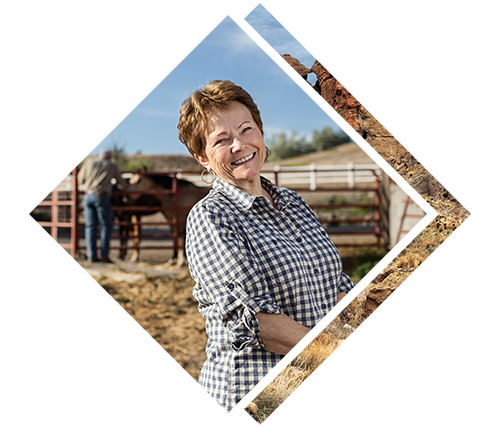 A women smiling with horses in the background